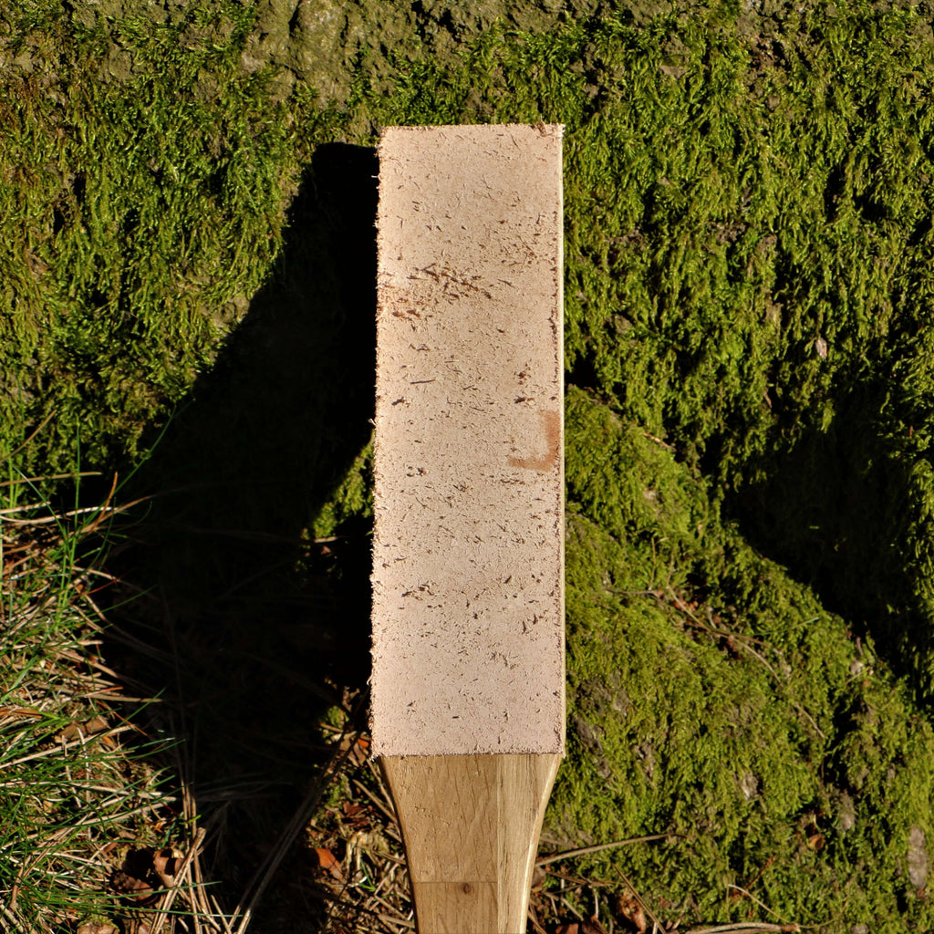 A knife sharpening paddle strop made from leather and wood