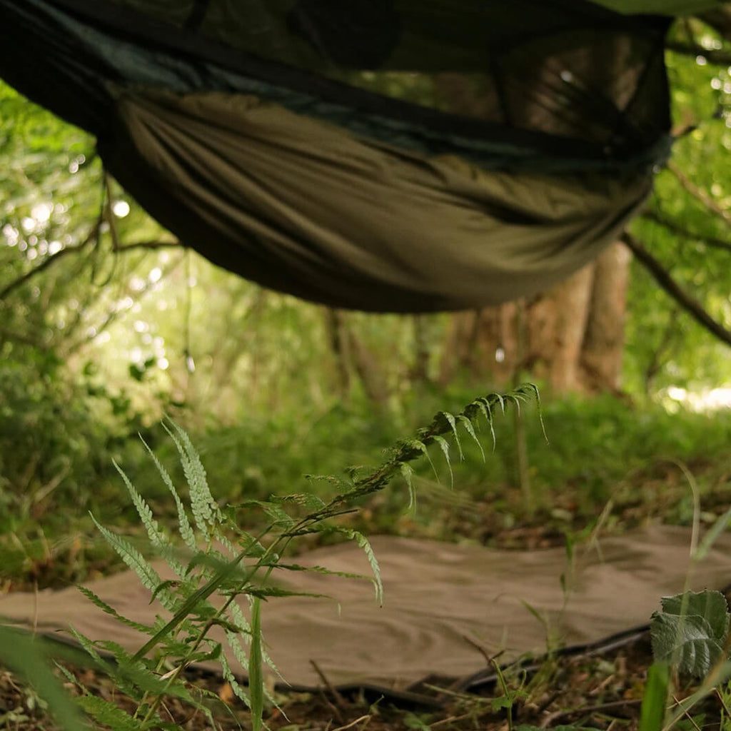 A wool and wax canvas blanket used as a groundsheet under a hammock and tarp camping setup