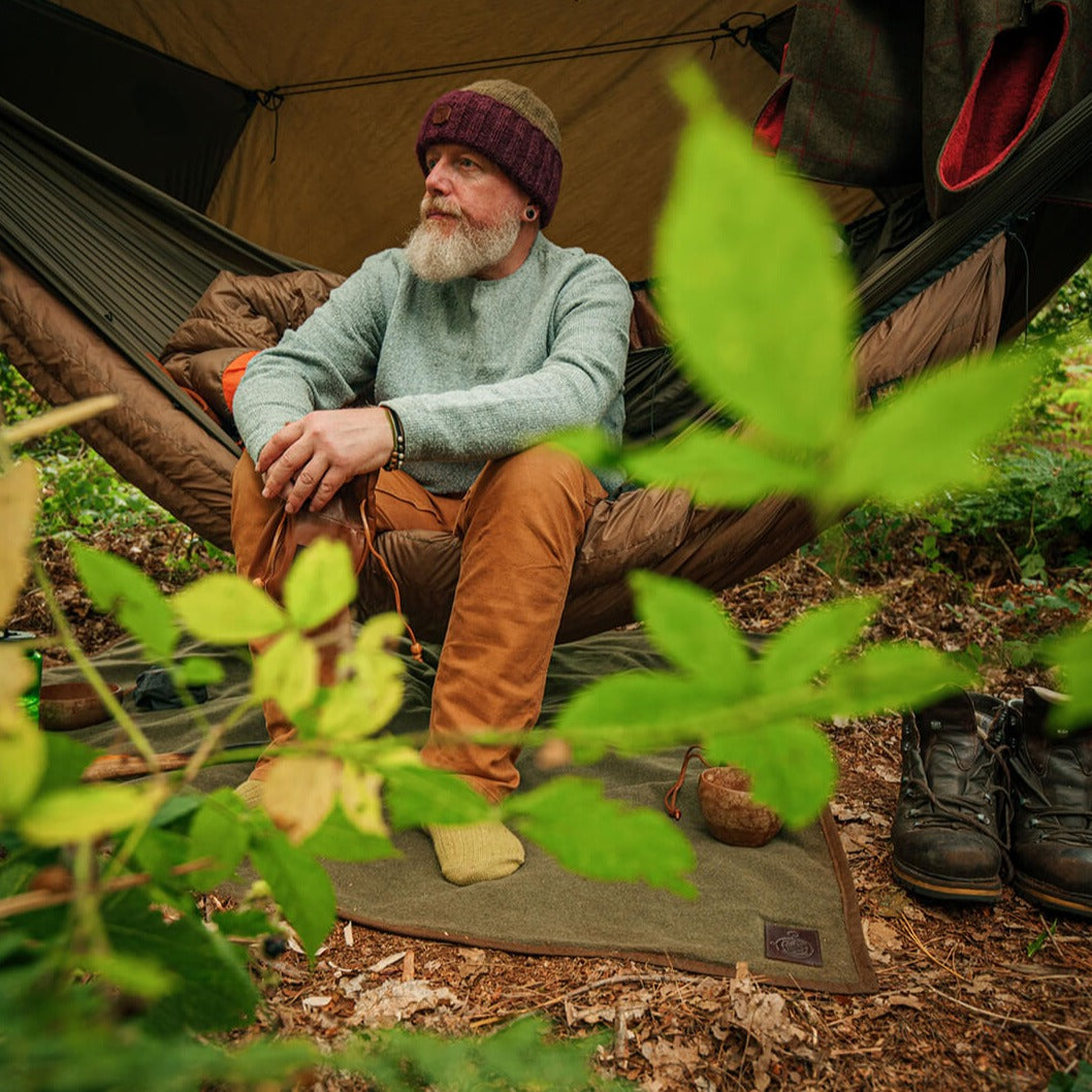 Man camping in the woods with a wool and wax canvas blanket