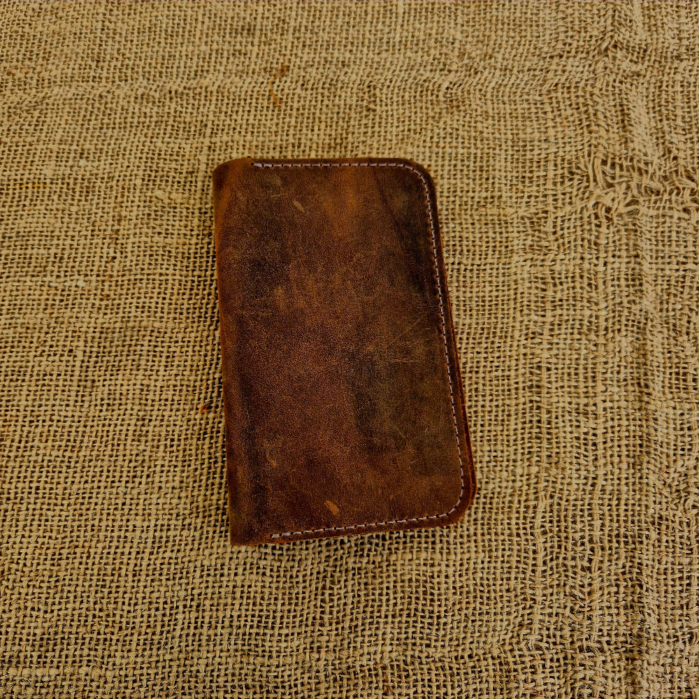 Brown leather notepad cover on a textured beige fabric background