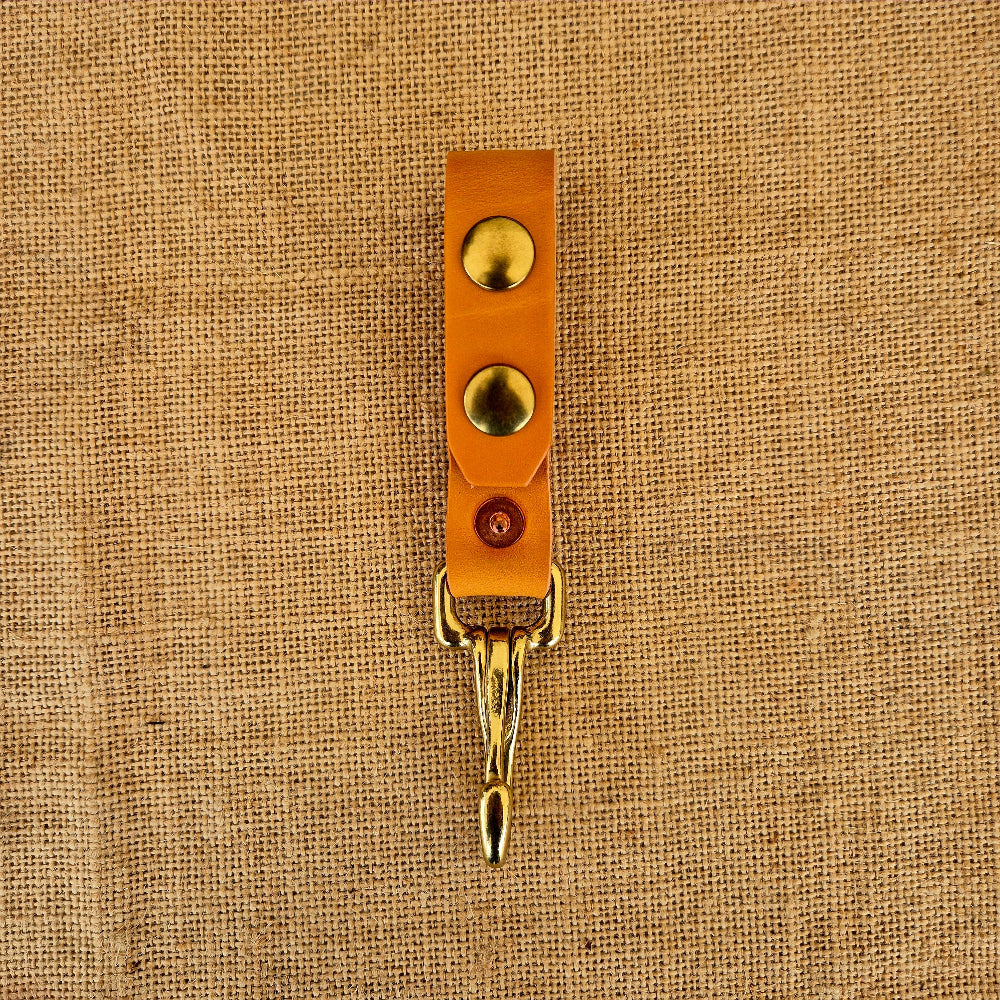 Leather strap with gold hardware on a beige fabric background