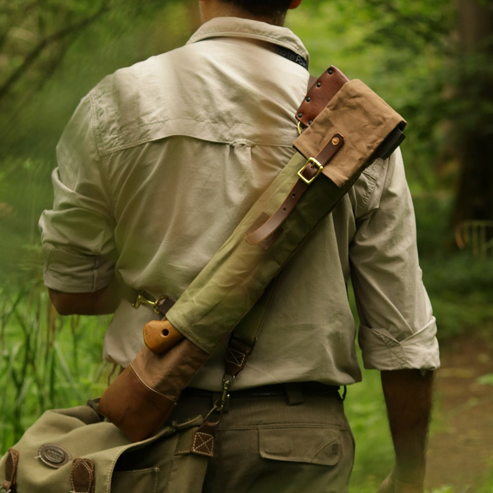 Man in the forest with a bucksaw and axe carry case