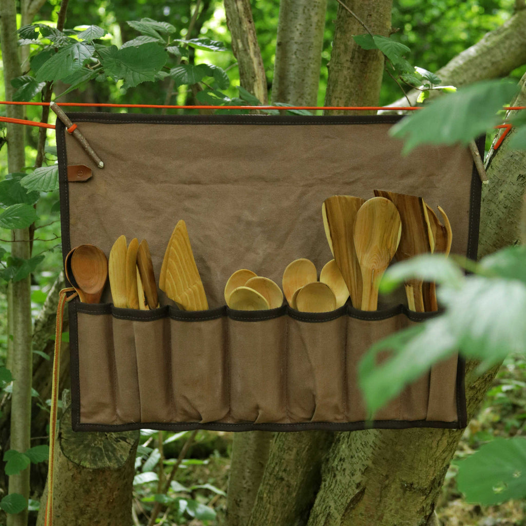 Brown canvas tool roll holding woodcarving spoons.