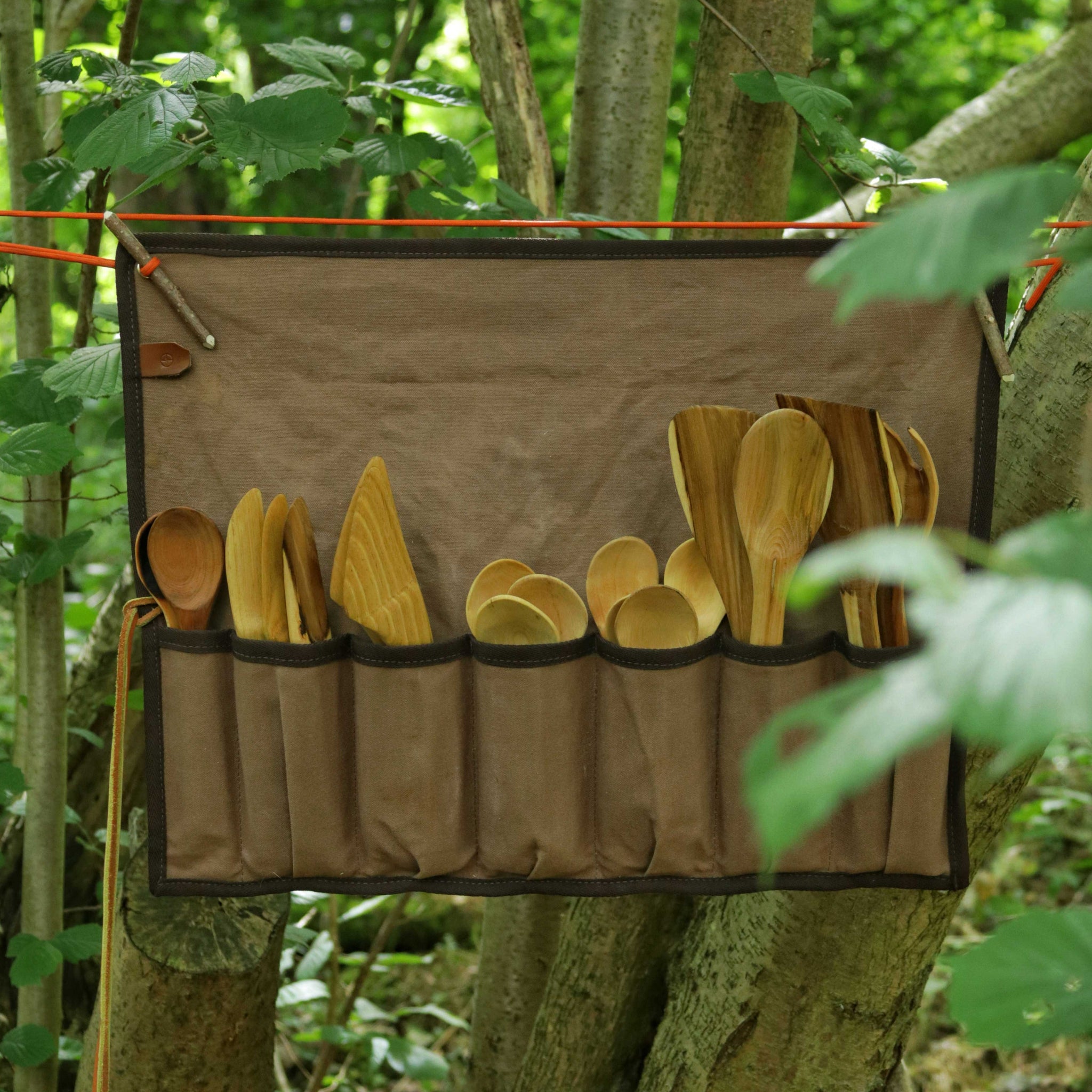 Brown canvas tool roll holding woodcarving spoons.