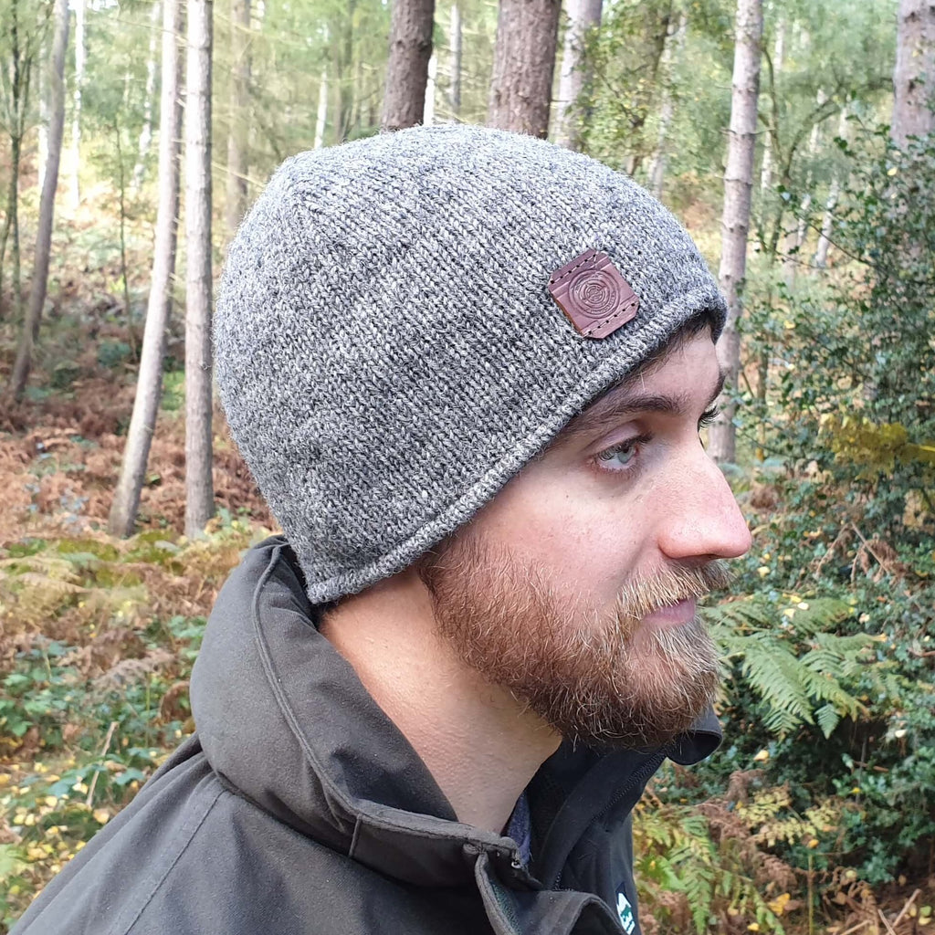 A man in the woods wearing a wool grey beanie hat