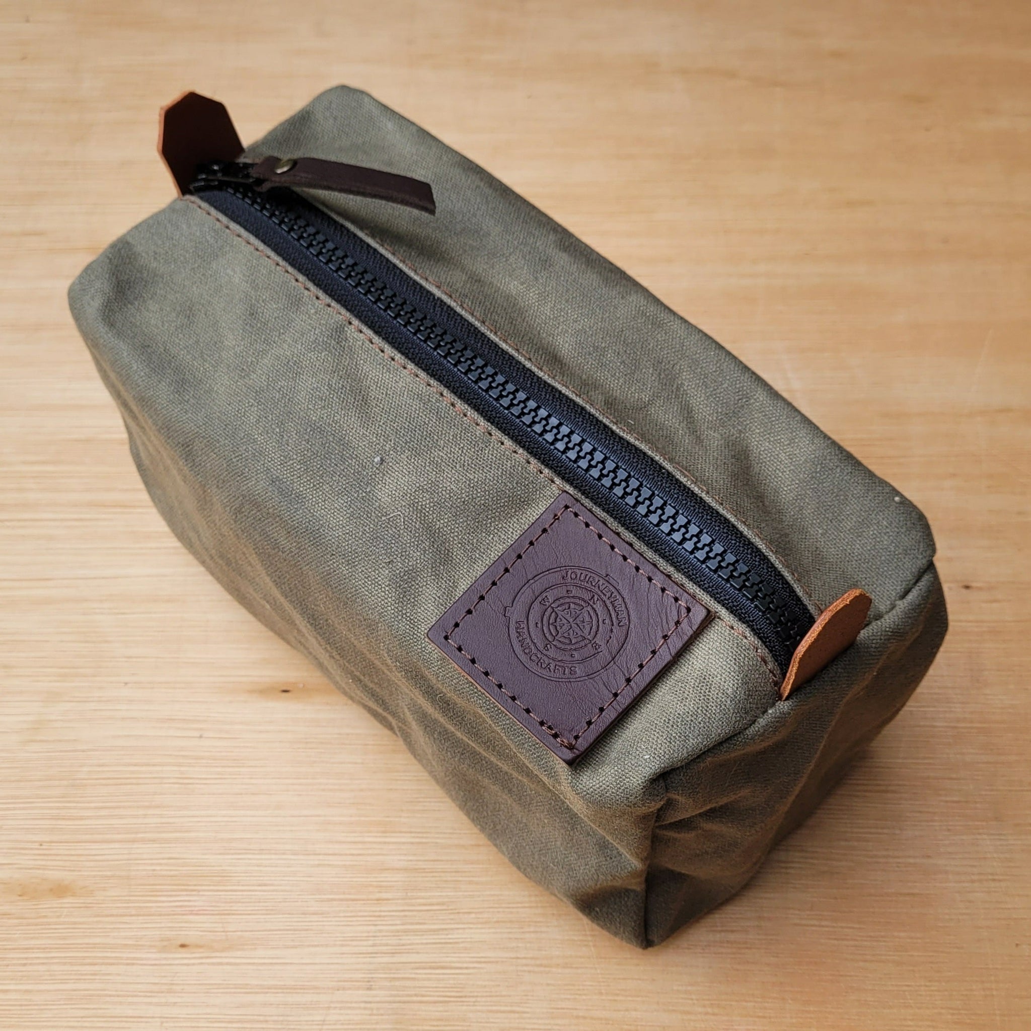 A green wax canvas pouch for carrying tent pegs