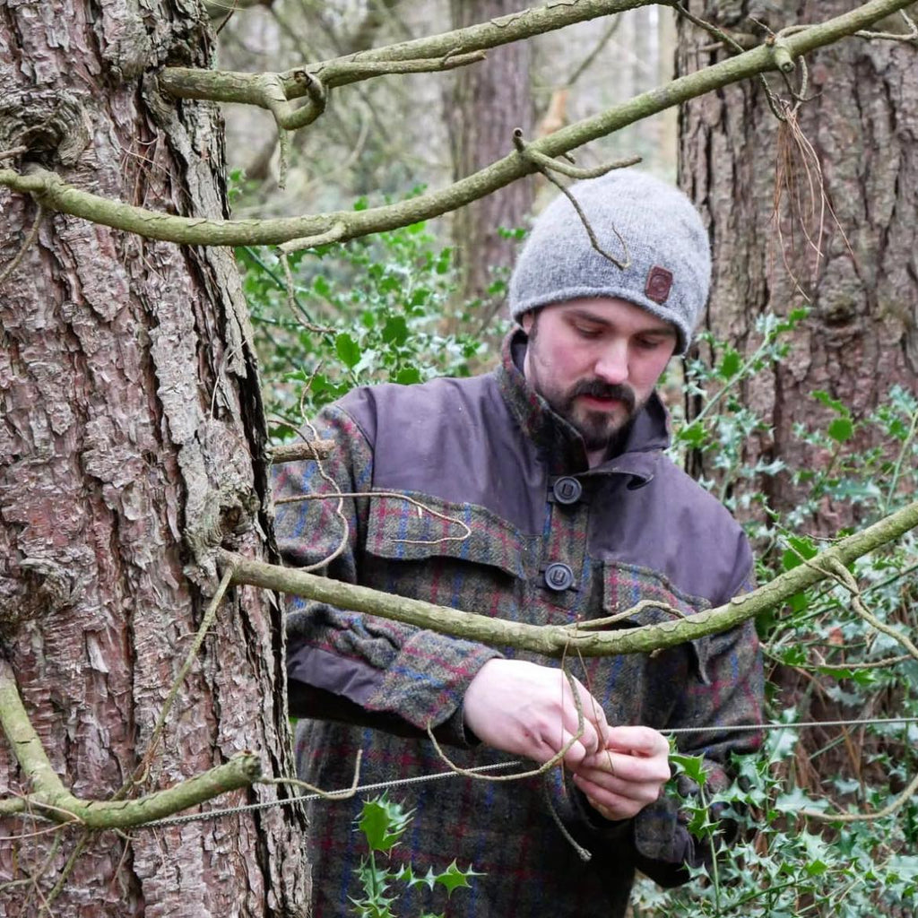 A man in the woods wearing a wool grey beanie hat