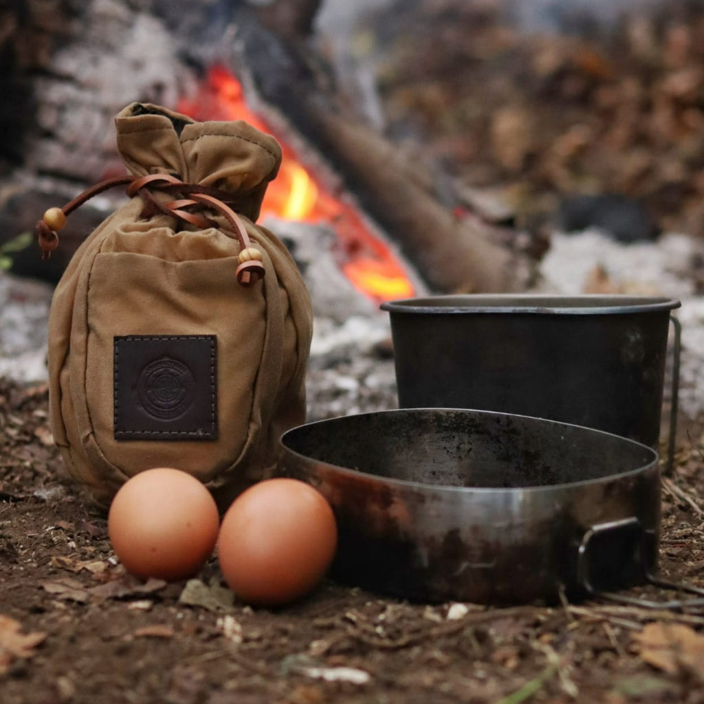 A Sami style wax canvas coffee pouch in khaki brown next to the campfire