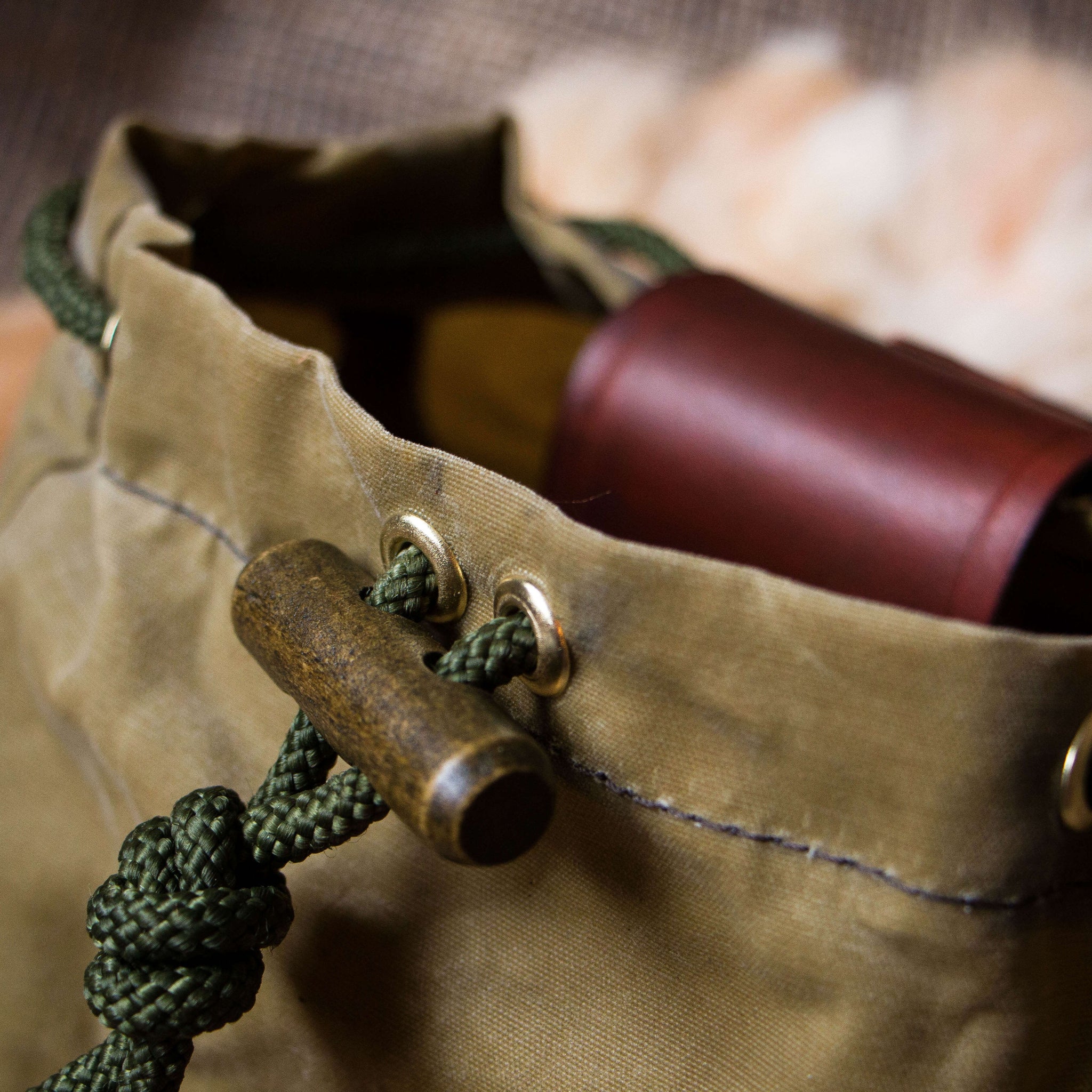 A wooden toggle on a forager dump pouch made from wax canvas and leather, used for foraging in the woods
