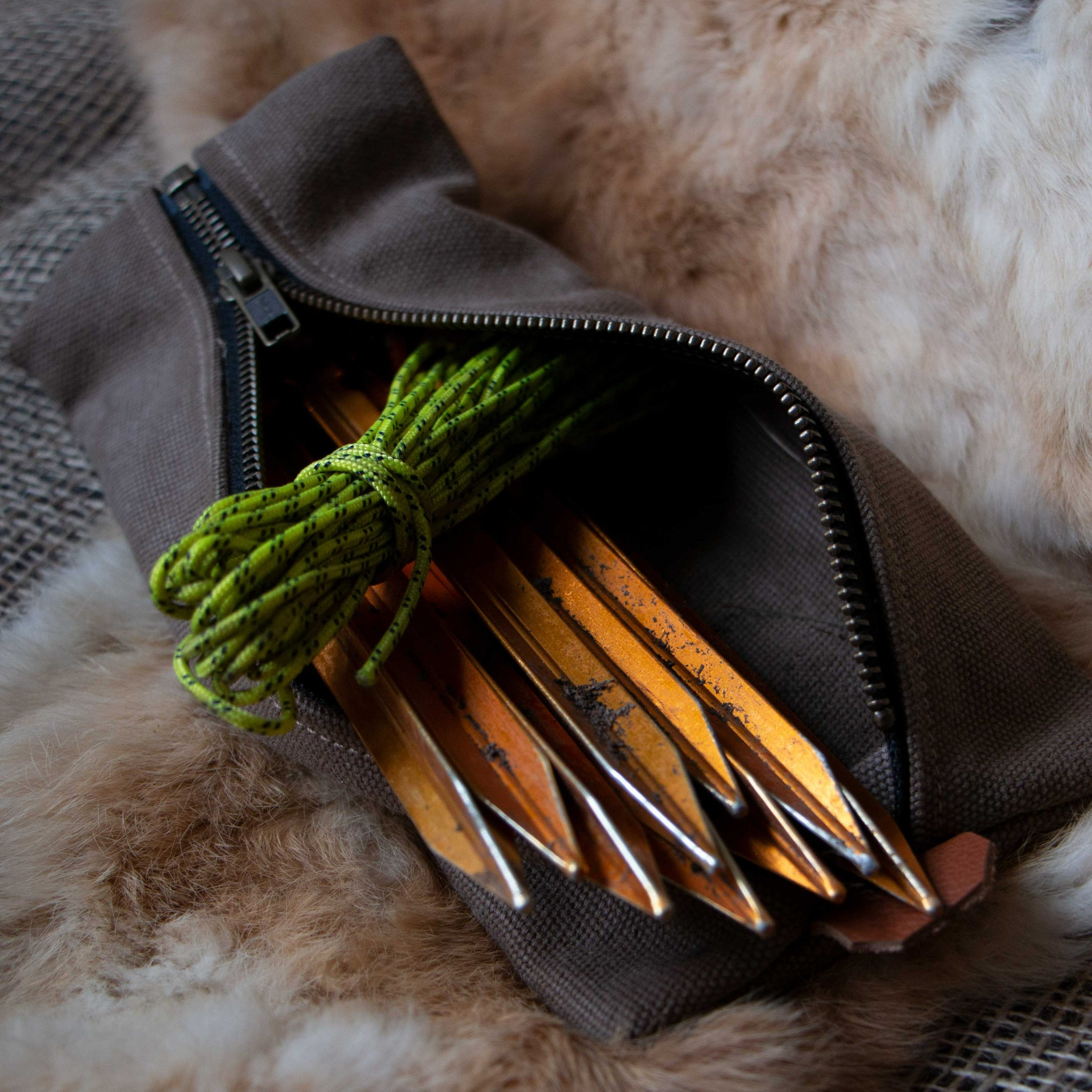 A brown canvas peg pouch with tent pegs inside