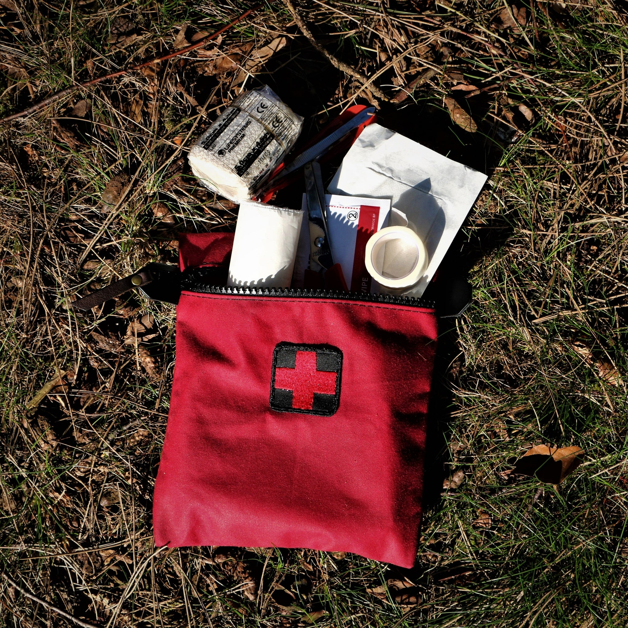 A red wax canvas first aid kit with essential first aid items