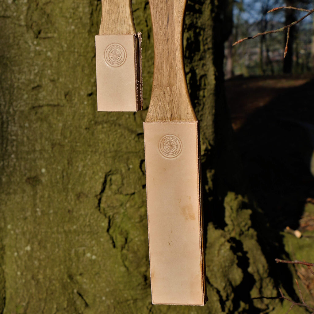 A small and large knife sharpening paddle strop made from leather and wood