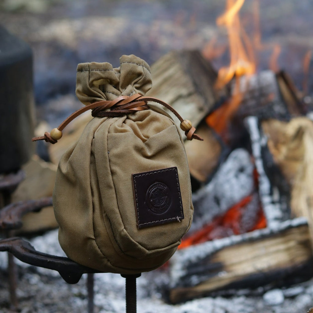 A traditional wax canvas coffee pouch by the campfire