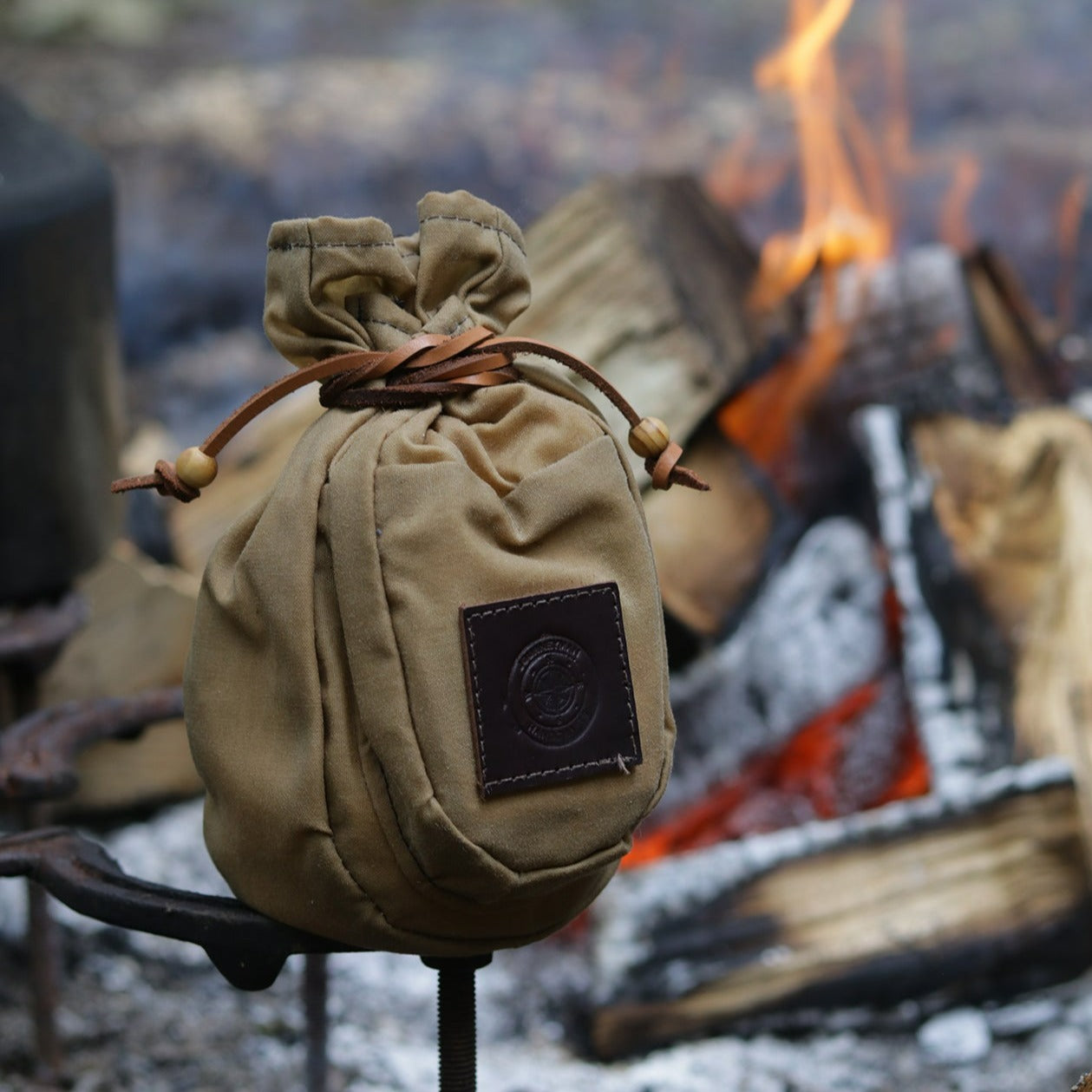 A traditional wax canvas coffee pouch by the campfire